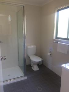 a bathroom with a toilet and a glass shower at Lorikeet Holiday Park in Arrawarra