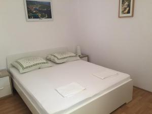 Una cama blanca con dos almohadas encima. en Apartments by the sea Basina, Hvar - 5700, en Vrboska