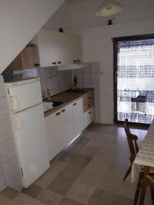 eine Küche mit weißen Geräten, einem Tisch und einem Fenster in der Unterkunft Holiday house with a parking space Zavala, Hvar - 5702 in Zavala