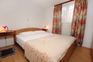 a bedroom with a bed and a window with curtains at Apartments by the sea Postira, Brac - 5672 in Postira