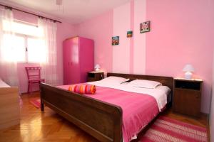 ein Schlafzimmer mit einem großen Bett mit rosa Wänden in der Unterkunft Apartments by the sea Ivan Dolac, Hvar - 5709 in Ivan Dolac