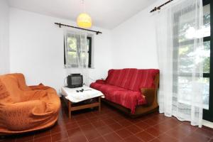 een woonkamer met een rode bank en een stoel bij Seaside secluded apartments Cove Zavala - Gdinj, Hvar - 5717 in Bogomolje