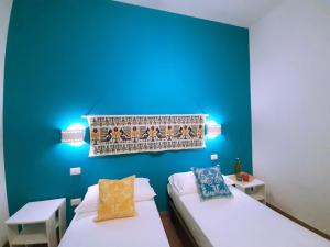een kamer met 2 bedden en een blauwe muur bij Camera Olbia Centro, vacanze Olbia e dintorni in Olbia