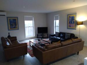 uma sala de estar com dois sofás e uma televisão em Splendour on Sackville em Albury