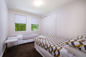 a bedroom with two beds and two windows at Splendour on Sackville in Albury