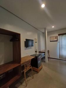 ein Wohnzimmer mit einem TV und einem Schreibtisch mit einem Tisch in der Unterkunft Acacia Garden Inn in Coron