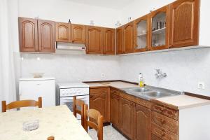 a kitchen with wooden cabinets and a sink and a table at Apartments by the sea Kali, Ugljan - 5828 in Kali