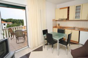 eine Küche mit einem Tisch und Stühlen sowie einen Balkon in der Unterkunft Apartment Zadar - Diklo 5774d in Zadar