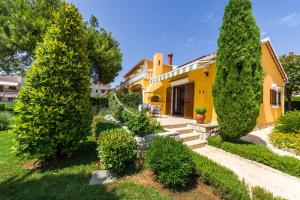 ein gelbes Haus mit Bäumen und Sträuchern in der Unterkunft Apartments with parking spaces Zadar - Diklo, Zadar - 5809 in Zadar