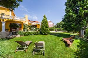 einen Garten mit Stühlen, einem Tisch und einem Haus in der Unterkunft Apartments with parking spaces Zadar - Diklo, Zadar - 5809 in Zadar
