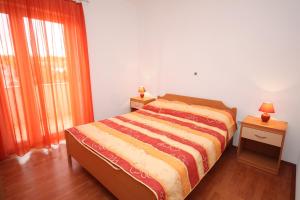 ein Schlafzimmer mit einem Bett, zwei Nachttischen und einem Fenster in der Unterkunft Apartment Vrsi - Mulo 5860b in Nin