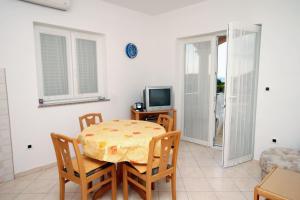 ein Esszimmer mit einem Tisch, Stühlen und einem TV in der Unterkunft Apartment Vrsi - Mulo 5860b in Nin
