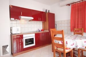 kuchnia z czerwonymi szafkami oraz stołem i krzesłami w obiekcie Apartment Vrsi - Mulo 5860c w Nin +13 zdjęć