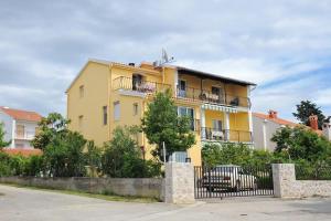 żółty dom z płotem przed nim w obiekcie Apartment Zadar - Diklo 5880d w mieście Zadar