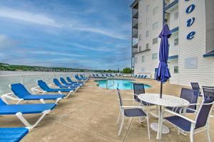 a patio with chairs and a table with an umbrella at Breezy Lake Ozark Escape Dock, Slip and Pool! in Lake Ozark