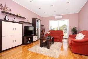 een woonkamer met rode stoelen en een flatscreen-tv bij Apartments by the sea Sukosan, Zadar - 5905 in Sukošan