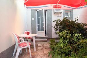 patio ze stołem, 2 krzesłami i parasolem w obiekcie Apartments and rooms with parking space Korcula - 4399 w Korčuli