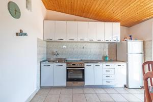 a kitchen with white cabinets and a refrigerator at Apartments by the sea Cove Pokrivenik, Hvar - 4604 in Gdinj