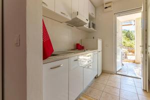 a kitchen with white cabinets and a red flag on the counter at Apartments by the sea Cove Pokrivenik, Hvar - 4604 in Gdinj