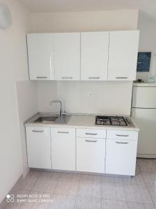 a white kitchen with a sink and a stove at Apartments by the sea Cove Pokrivenik, Hvar - 4604 in Gdinj