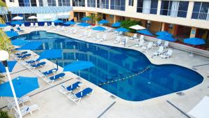 uma vista sobre uma piscina com cadeiras e guarda-sóis azuis em Ritz Acapulco All Inclusive em Acapulco