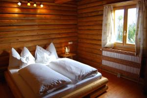 a bedroom with a bed with white pillows and a window at Boróka Apartmanházak - Gerenda Ház in Velem