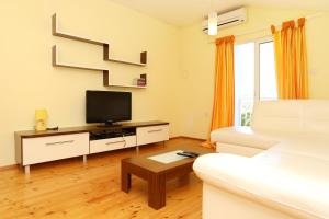 uma sala de estar com um sofá branco e uma televisão em Apartment Zuljana 4576a em Žuljana