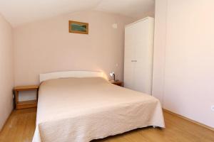 a white bedroom with a bed and a door at Apartment Zuljana 4576a in Žuljana
