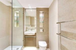 a bathroom with a toilet and a sink and a shower at Riverside apartment minutes from Elizabeth line in London