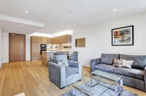 a living room with two couches and a kitchen at Riverside apartment minutes from Elizabeth line in London