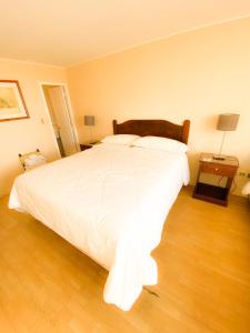 una camera da letto con un grande letto bianco e un pavimento in legno di Hotel Londres La Serena a La Serena