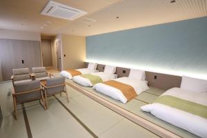 宮若市にある宮若温泉郷 宮若虎の湯 Miyawaka Toranoyuのベッド4台、テーブルと椅子が備わる客室です。