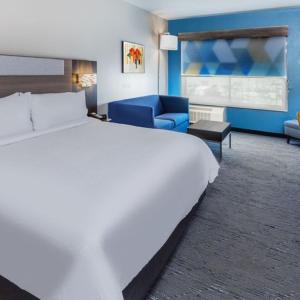 - une chambre avec un grand lit blanc et un canapé bleu dans l'établissement Holiday Inn Express & Suites - Houston SW - Rosenberg, an IHG Hotel, à Rosenberg