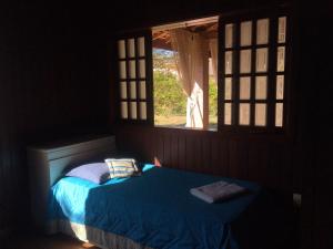 a bedroom with a blue bed with a window at Chalé Aconchegante in Maria da Fé