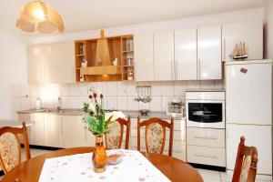 kuchnia z białymi szafkami i stołem z kwiatami w obiekcie Apartments with a parking space Zavalatica, Korcula - 4458 w mieście Zavalatica +13 zdjęć
