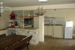 a kitchen with a fireplace and a table and a refrigerator at Apartment Brna 4468a in Brna