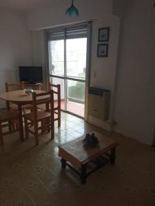 d'un salon avec une table, des chaises et une fenêtre. dans l'établissement Santa Teresita frente al Mar, à Santa Teresita