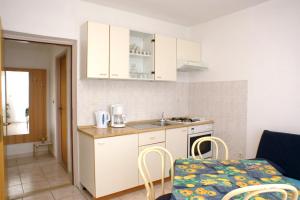 una pequeña cocina con armarios blancos, mesa y sillas en Apartments by the sea Lumbarda, Korcula - 4402, en Lumbarda