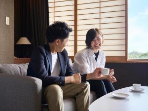 dos mujeres sentadas en una habitación hablando y riendo en Hotel Flags Kuju Kusima, en Sasebo