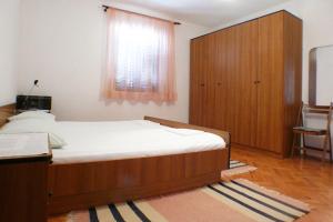a bedroom with a bed and a wooden cabinet at Apartments by the sea Karbuni, Korcula - 4465 in Prizba