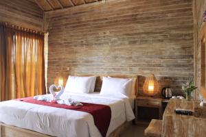 a bedroom with a bed and a wooden wall at The Pancor Jungle Resort in Nusa Penida