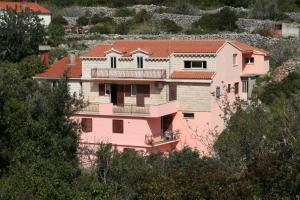 a pink house on a hill with trees at Apartments by the sea Racisce - Korcula - 4359 in Račišće