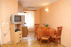 a kitchen and dining room with a table and a television at Apartments by the sea Trstenik, Peljesac - 4511 in Trstenik