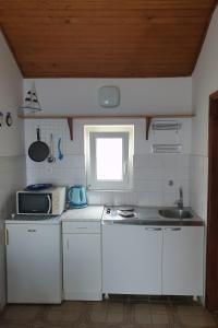 uma cozinha com armários brancos, um lavatório e uma janela em Studio Dingac - Potocine 4533a em Potomje