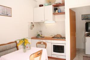 a small kitchen with white cabinets and a table at Apartments and rooms by the sea Trstenik, Peljesac - 4566 in Trstenik