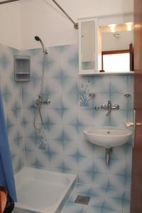 a blue tiled bathroom with a sink and a shower at Apartments and rooms by the sea Trstenik, Peljesac - 4566 in Trstenik