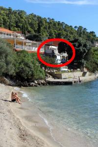 a red sign on a beach next to the water at Apartments by the sea Brna, Korcula - 4425 in Smokvica