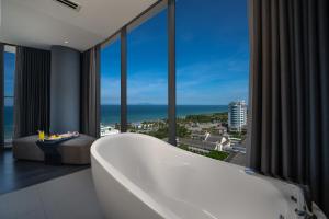 Draco Hotel & Suites في دا نانغ: حمام مع حوض استحمام وإطلالة على المحيط