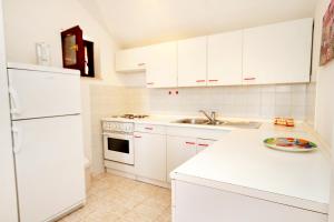 a white kitchen with white cabinets and a sink at Apartments by the sea Kneza, Korcula - 4371 in Pupnat