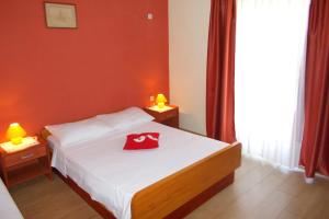 ein Schlafzimmer mit einem Bett mit einem roten Hut darauf in der Unterkunft Apartment Kneza 4342a in Račišće